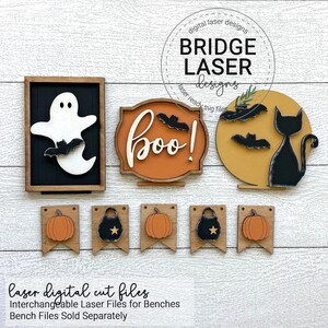 May include: Halloween-themed wooden decorations. Includes a ghost, the word "boo!" with bats, a black cat silhouette, pumpkins, and cauldrons. The decorations are in shades of orange, black, and white, with a wooden frame.