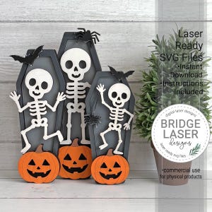 May include: Three gray coffin-shaped cutouts featuring white skeleton figures and orange jack-o'-lanterns at the base. The design includes black bat and spider accents. Text on the right reads Laser Ready SVG Files Instant Download.