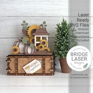 Op de afbeelding: Een gelaagd houten knutselproject met pompoenen, zonnebloemen en een lantaarn op een rechthoekige doos. Een label aan de voorzijde toont "GATHER Together" met twee kleine hartjes. De tekst rechts luidt "Laser Ready SVG Files".