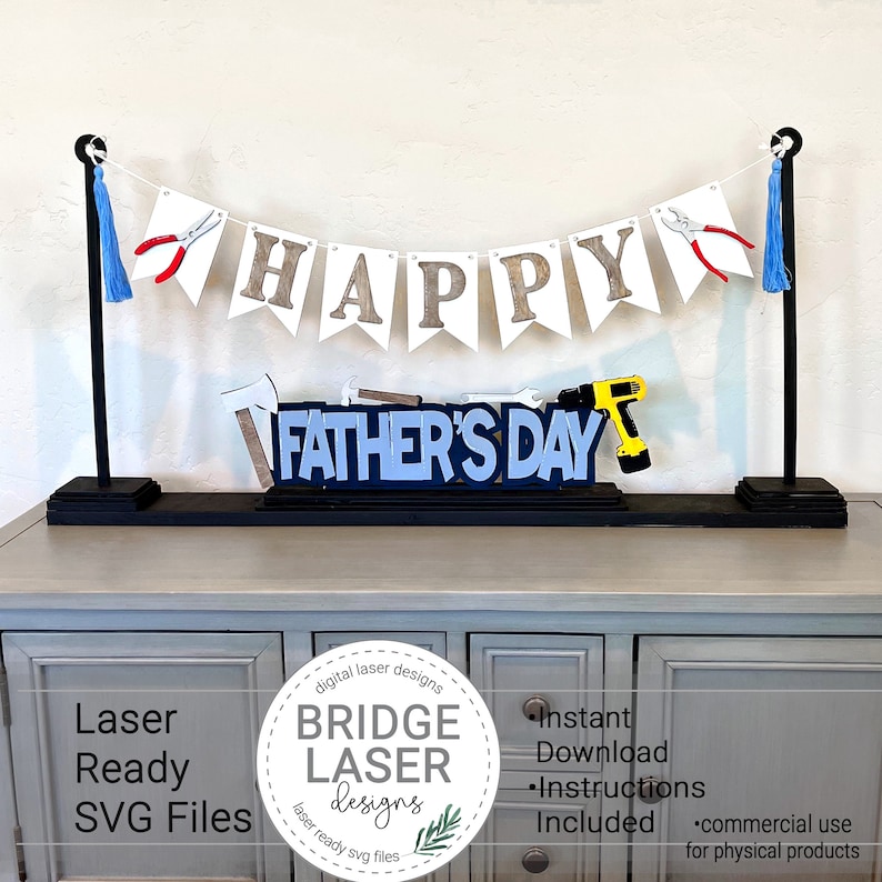 May include: A Father's Day banner with the words "HAPPY FATHER'S DAY" in a decorative design. The banner includes tools and blue tassels. The design is displayed on a black base.