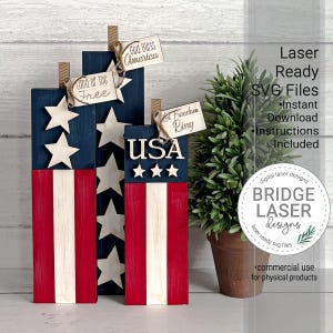 May include: Wooden American flag decorations with red and white stripes, blue fields with white stars, and attached tags that read "God Bless America", "Land of the Free", and "Let Freedom Ring". The word "USA" is also displayed.