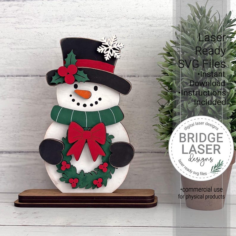 K&ouml;nnte beinhalten: Ein Schneemann-Ausschnitt aus Holz auf einem rechteckigen Sockel. Der Schneemann tr&auml;gt einen schwarzen Zylinder mit rotem Band, einer wei&szlig;en Schneeflocke und Stechpalmenbeeren. Er hat eine orangefarbene Karottennase, einen gr&uuml;nen Schal und einen Kranz.