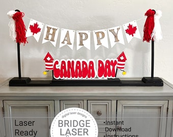 May include: A red and white "Happy Canada Day" banner with fireworks and a red maple leaf. The banner is displayed on a black stand with white tassels.