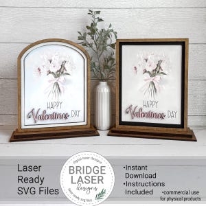 Puede incluir: Dos letreros de madera del Día de San Valentín con ramos de flores y el texto "HAPPY Valentines DAY". Un letrero es arqueado, el otro rectangular. Los letreros están sobre una base de madera. Un jarrón blanco con vegetación está entre los letreros.
