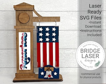 May include: A wooden sign with a red, white, and blue American flag, a bell, and the word "America" on it. The sign is designed for laser cutting and comes with instructions.
