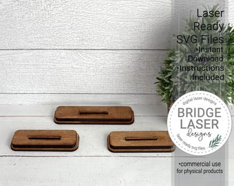 May include: Three rectangular wooden laser-cut pieces with a slot in the center. The pieces are brown with a dark brown edge. The image also includes text that says "Laser Ready SVG Files" and "BRIDGE LASER Designs".