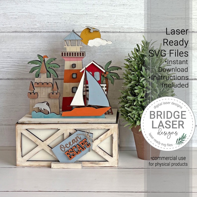 Op de afbeelding: Een meerlaagse houten display met een vuurtoren, zeilboot, zandkasteel en palmbomen op een witte rechthoekige basis met een X-patroon. Een blauw label aan de voorzijde bevat de tekst Ocean ESCAPE. De tekst rechts luidt Laser Ready SVG Files.