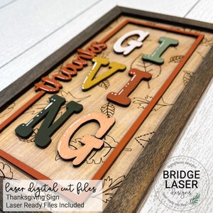 Peut inclure: Une pancarte en bois avec un cadre brun et un fond blanc. La pancarte dit "Giving Thanks" en lettres color&eacute;es avec un motif de feuilles d'automne. La pancarte est d&eacute;coup&eacute;e au laser et pr&ecirc;te &agrave; &ecirc;tre assembl&eacute;e.