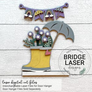 Puede incluir: Un dise&ntilde;o de archivo de corte l&aacute;ser para un colgador de puerta que presenta una bota de lluvia amarilla con flores moradas, hojas verdes y una sombrilla gris. El dise&ntilde;o tambi&eacute;n incluye una pancarta con arco&iacute;ris y sombrillas.