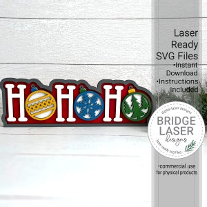 May include: A wooden Christmas decoration spelling "HOH" with ornaments. The letters are white, outlined in gray, and set against a red background. The ornaments are yellow, blue, and green. The text "Laser Ready SVG Files" is also visible.