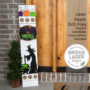 May include: A white wooden sign with a witch, cauldron, and bats. The sign also has a chalkboard with the text "Welcome My Pretties" and three glass bottles with colored liquids. The sign is leaning against a brick wall and a wooden door. The text "Laser Ready SVG Files" is in the upper right corner of the image. The text "Instant Download" and "Instructions Included" are below the text "Laser Ready SVG Files". The text "digital laser designs" and "BRIDGE LASER designs" are in a circle in the lower right corner of the image. The text "laser ready svg files" is below the text "BRIDGE LASER designs". The text "commercial use for physical products" is below the circle.