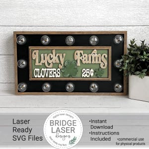 May include: A wooden sign with a black background and white light bulbs around the border. The sign says "Lucky Farms" in green and gold lettering with a shamrock design. The sign also says "Clovers 25¢" in white lettering.