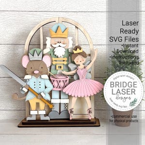 Puede incluir: Una decoración navideña de madera cortada con láser que presenta personajes del ballet El Cascanueces. Las figuras incluyen un cascanueces, un ratón y una bailarina, sobre un fondo en forma de ventana. El texto de la imagen dice "Laser Ready SVG Files".