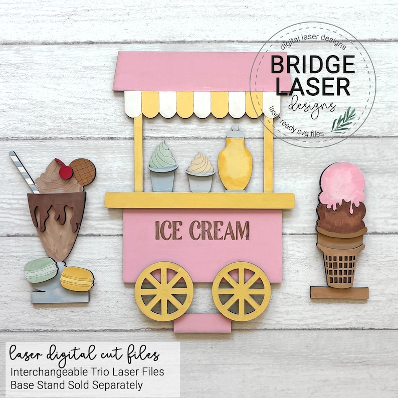 May include: A wooden ice cream cart with a pink awning, yellow wheels, and the words "ICE CREAM." The cart is accompanied by a chocolate milkshake, a waffle cone with ice cream, and macarons. The image includes the text "Laser digital cut files."