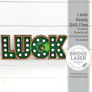 May include: A wooden "LUCK" sign with a green shamrock and gold star in the center of the "C". The sign has a wood frame and white polka dots on a green background.