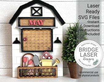 May include: A laser cut wooden calendar in the shape of a barn with a May calendar insert. The calendar is decorated with flowers, a watering can, and a gardening tool. The calendar is ready to be assembled and painted.
