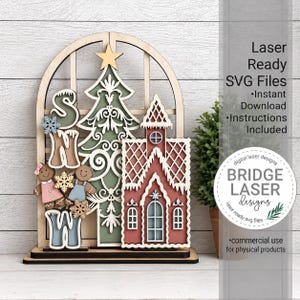Pode incluir: Um enfeite de madeira cortado a laser com várias camadas, apresentando uma moldura de janela em arco, uma árvore de Natal decorativa com uma estrela, uma casa de gengibre e dois bonecos de gengibre. O texto "SNOW" inclui flocos de neve.