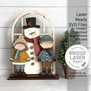 May include: A wooden winter-themed decoration featuring a snowman and two children, all in winter attire. The snowman has a black hat and red scarf. The children wear coats and hats. The text "Laser Ready SVG Files" and "Bridge Laser Designs" are visible.