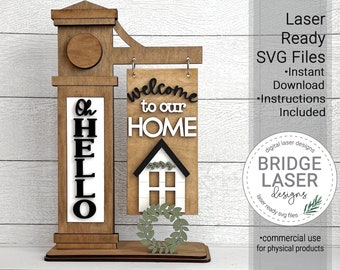 May include: Laser cut wooden welcome sign with a house and wreath design. The sign says "Welcome to our Home". There is a separate sign that says "Oh Hello".