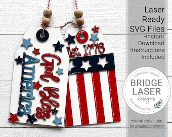 May include: Two white wooden tags with red, white, and blue patriotic designs. One tag says "God Bless America" and the other says "Est. 1776".