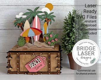 May include: A wooden box with a beach-themed topper featuring surfboards, a multi-colored umbrella, palm trees, and a yellow sun. A pink tag attached to the front reads "BEACH time" in white and dark lettering. The design includes layered cutouts.