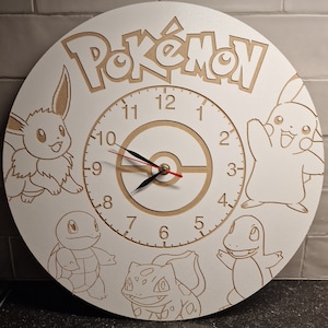 Könnte beinhalten: Eine weiße Holzuhr mit Pokemon-Motiv. Das Zifferblatt der Uhr zeigt eine Uhr mit römischen Ziffern und einem Pokeball-Design. Die Uhr ist von Bildern von Pokemon-Charakteren umgeben, darunter Pikachu, Bisasam, Glumanda und Schiggy.