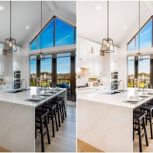 May include: A modern kitchen with white cabinets, a large island with black bar stools, and a large window with a view of a suburban neighborhood. The kitchen has two black pendant lights hanging over the island.