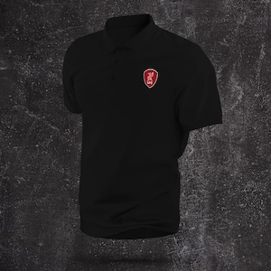 May include: Black polo shirt with short sleeves and a collared neckline. A red and white emblem is on the left chest. The shirt is made of a soft material and is suitable for casual wear.
