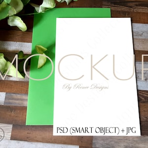 Könnte beinhalten: Ein weißer Karten-Mockup mit dem Text "MOCKUP By Renee Designs PSD (SMART OBJECT) + JPG" auf einer grünen Karte und einem Holz-Hintergrund.