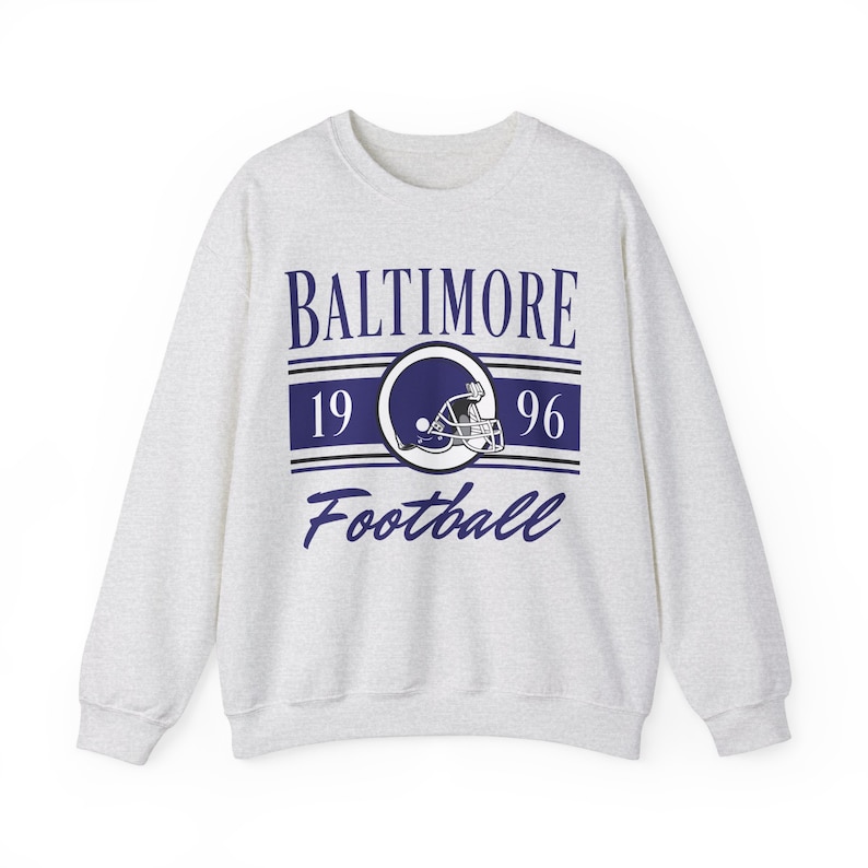 Light ash gray sweatshirt with a retro vintage Baltimore Football design on the front, including the founding date (1996) of the Baltimore Ravens, and a seating chart layout design of M&T Bank Stadium across the back.