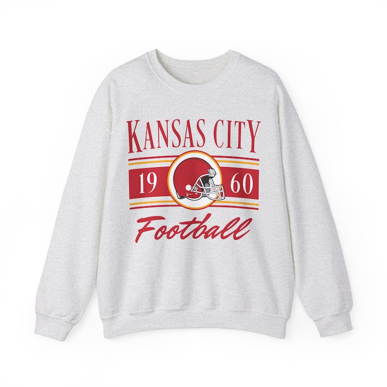 Light ash gray sweatshirt with a retro vintage Kansas City Football design on the front, including the founding date (1960) of the Kansas City Chiefs, and a seating chart layout design of Arrowhead Stadium across the back.