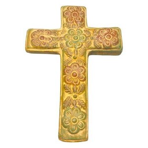 May include: A decorative cross with a floral design. The cross is a golden yellow color with embossed flowers in shades of brown and green. The flowers are arranged in a symmetrical pattern across the cross.