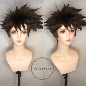 May include: A brown cosplay wig with a spiky style. The wig is on a mannequin head and is styled with a side part. The wig is on a white background. The text "Hyperwigs" is visible in the bottom center of the image.