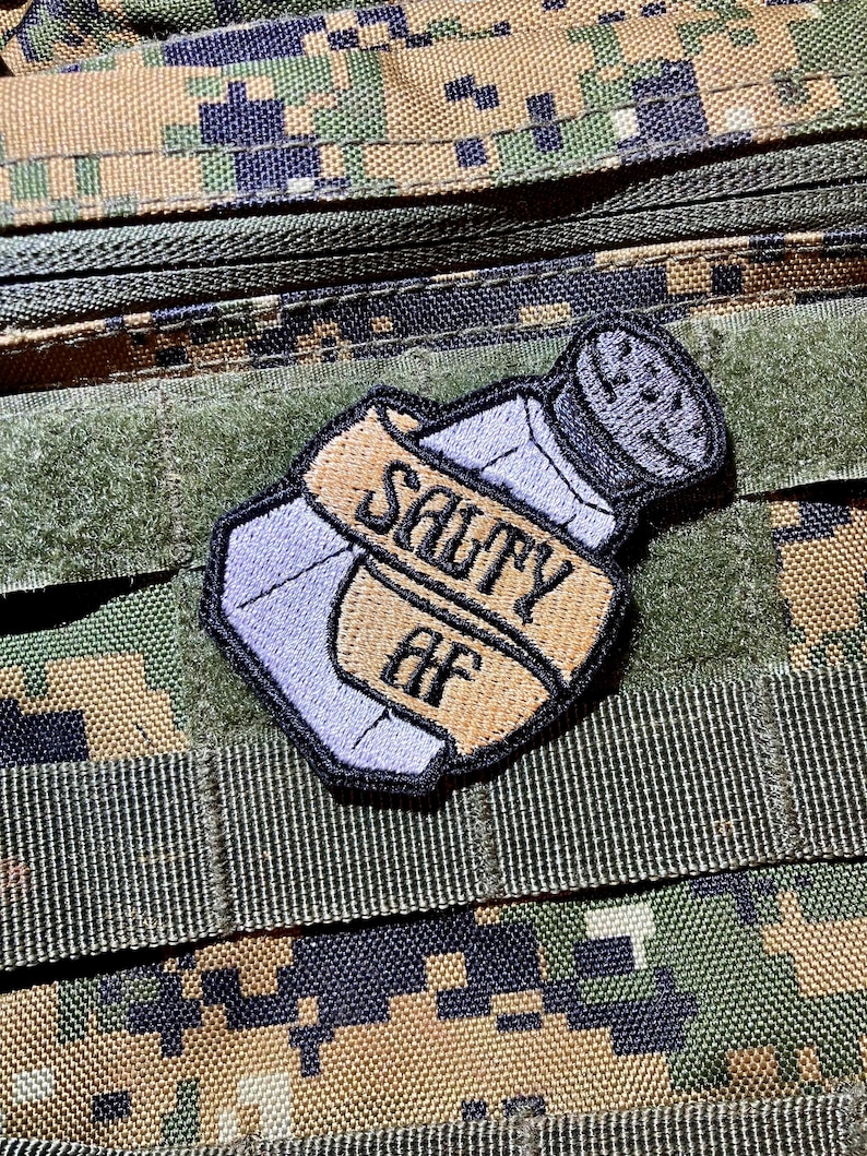 May include: A salt shaker with a brown ribbon that says "Salty AF" on it. The salt shaker is embroidered on a patch.