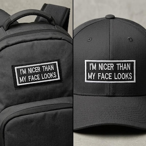 Peut inclure: Un sac à dos noir et une casquette de baseball noire assortie, tous deux dotés d'un écusson rectangulaire avec le texte brodé en blanc I'M NICER THAN MY FACE LOOKS. Les articles sont fabriqués dans un tissu durable avec un design structuré.