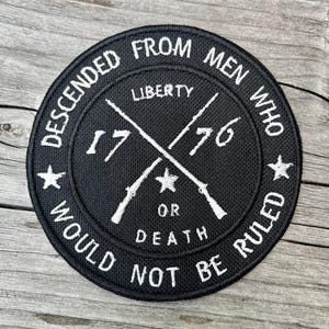 May include: Black circular patch with white embroidered text and design. The text reads "DESCENDED FROM MEN WHO WOULD NOT BE RULED" and includes "1776" and crossed rifles. Stars and the word "LIBERTY" are also present.