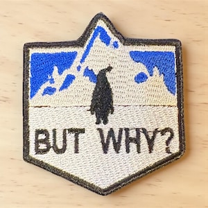 May include: Embroidered patch featuring a black penguin silhouette against a blue mountain range. The patch displays the text "BUT WHY?" in white. The patch is bordered by a black trim and has a light beige background.