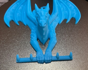 May include: A light blue dragon wall hook with three hooks. The dragon is in a crouching position with its wings spread out.
