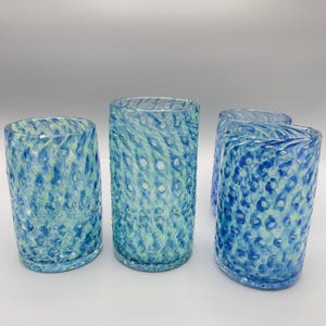 May include: Set of four blue and green glass tumblers with a textured, bubbled surface. The glasses are cylindrical and have a clear, slightly frosted appearance.