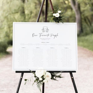 May include: A white wedding seating chart with a black frame and the text "Our Favorite People" with the names Benjamin & Jennifer and the date December 12, 2021. The chart lists the names of guests assigned to each table.