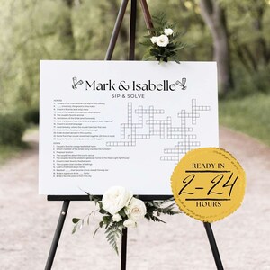 May include: A white sign with a black crossword puzzle on an easel. The sign says "Mark & Isabelle Sip & Solve" and has a gold circle with the text "Ready in 2-24 Hours".