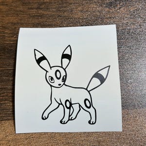 May include: A black and white line drawing of a Pokemon character, Espeon, on a white background.