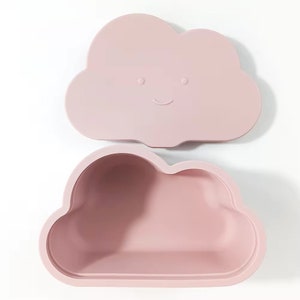 May include: A pink cloud-shaped silicone container with a lid. The lid has a smiling face.