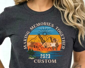 May include: A dark gray t-shirt with a vintage-style graphic of a bear and a mountain scene. The graphic says "Making Memories Together 2023 Custom".
