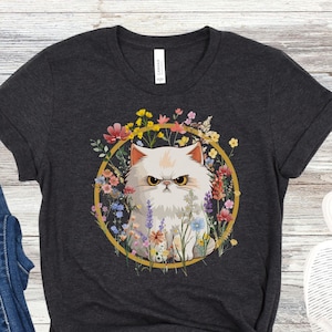 May include: A dark gray t-shirt with a white cat surrounded by colorful flowers in a gold circle. The cat has a grumpy expression.