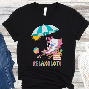 May include: Black t-shirt featuring a cartoon axolotl wearing sunglasses and holding a drink, sitting on a beach chair under an umbrella with a beach ball and pineapple. The text "RELAXOLOTL" is printed below the axolotl.