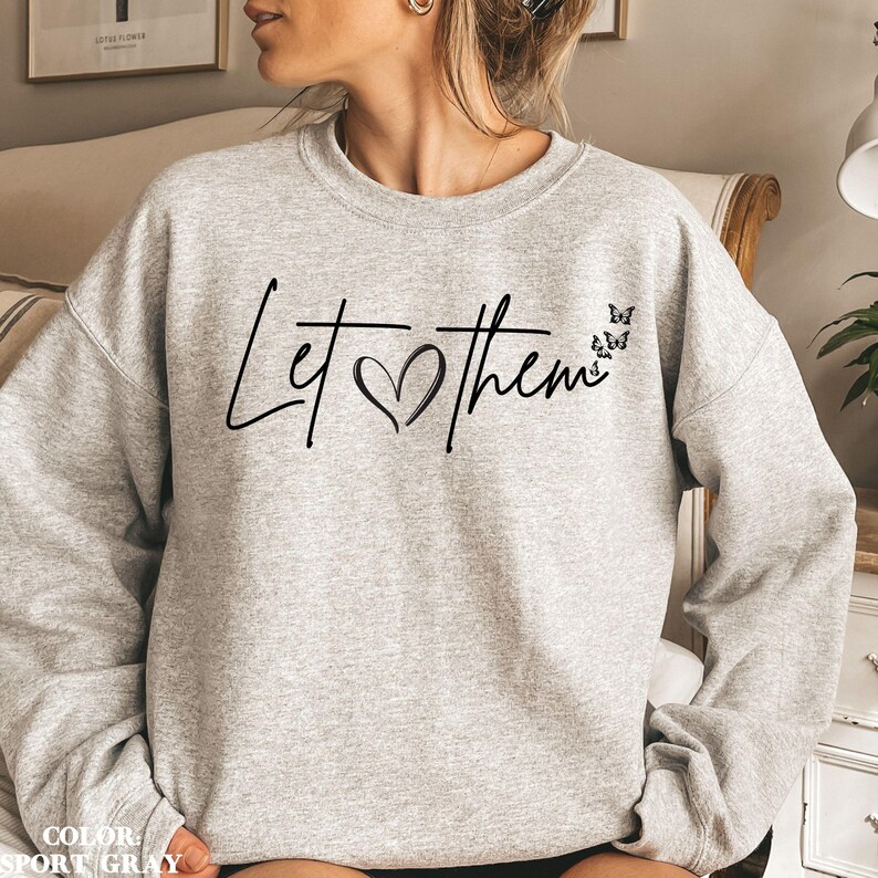 May include: A gray sweatshirt with the text "Let &hearts; them" in black script with a heart and four black butterflies.