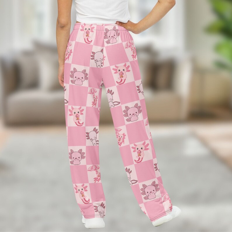 Peut inclure: Pantalon de pyjama rose avec un motif &agrave; carreaux repr&eacute;sentant des axolotls de dessin anim&eacute;. Les axolotls sont dans diverses poses, certains tenant des parapluies ou des cornets de cr&egrave;me glac&eacute;e. Le pantalon a une coupe large et une taille &eacute;lastique.