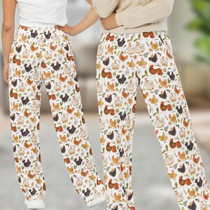 May include: White pajama pants with a repeating pattern of colorful chickens. The pants have an elastic waistband and a relaxed fit.