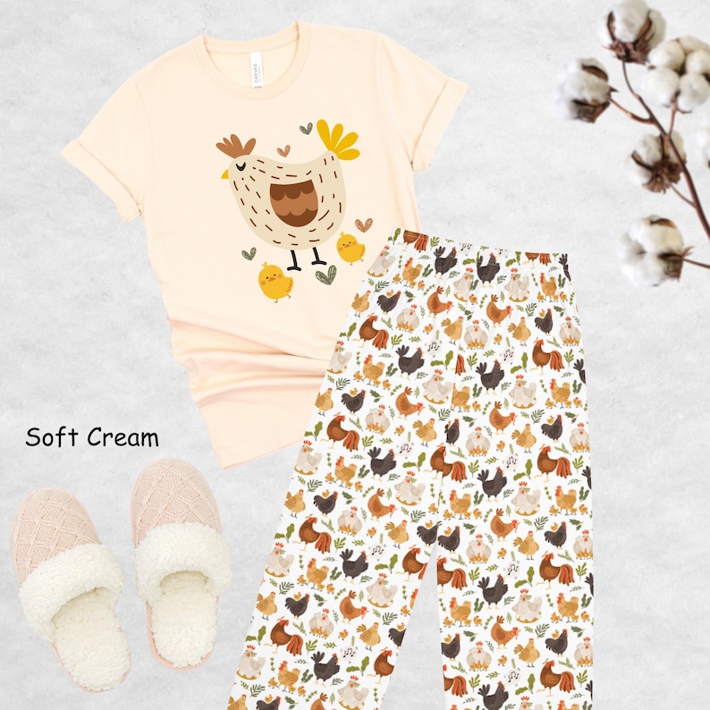 May include: A soft cream colored t-shirt with a cartoon illustration of a hen and chicks. The t-shirt is paired with white pajama pants with a repeating pattern of hens and chicks.